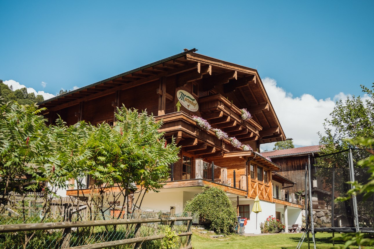 Martenhof mit Garten und Holzfassade im Sommer